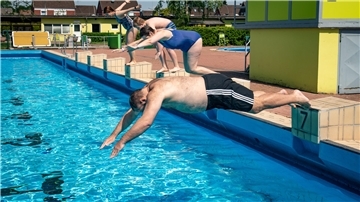 Menschen springen in ein Freibad
