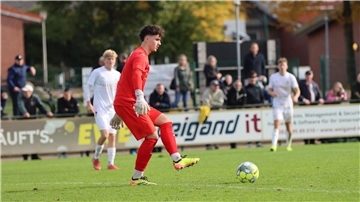 Ein Mann in rotem Trikot schießt einen Ball.