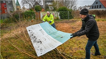 13 Jahre lang erklärte das Transparent am Ex-Reinigungsstandort Poststraße 18 das Sanierungsprojekt des Umweltamtes. Martin Albers (rechts) und Lutz Becker vom Umweltschutzamt können das Schild nun „entrümpeln“ .