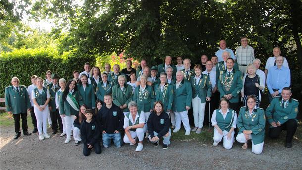 Drangstedter Schützen feiern 150 Jahre mit großem Festakt Gruppenfoto des Schützenvereins Drangstedt zum 150-jährigen Jubiläum: Über 40 Vereinsmitglieder und Gäste in grüner Schützenkleidung und Alltagskleidung posieren bei sonnigem Wetter vor einem Baum und dichten Hecken.