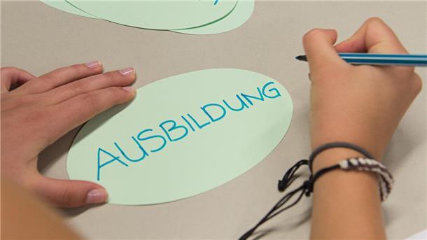 Ein Zettel mit der Aufschrift "Ausbildung" liegt in einem Klassenzimmer auf einem Tisch