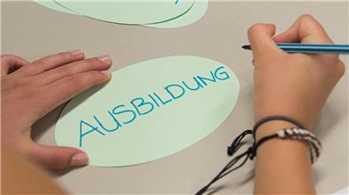 Ein Zettel mit der Aufschrift "Ausbildung" liegt in einem Klassenzimmer auf einem Tisch
