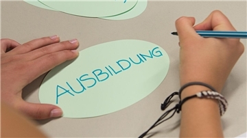 Ein Zettel mit der Aufschrift "Ausbildung" liegt in einem Klassenzimmer auf einem Tisch
