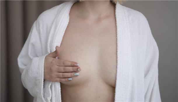 Eine Frau legt die Hand auf ihre Brust