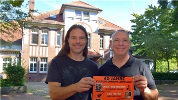 Zwei Männer mit Plakat in den Händen vor einem Gebäude