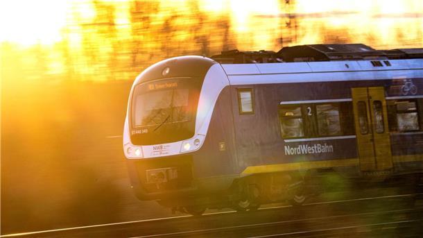 Ein Zug der Nordwestbahn vor der untergehenden Sonne.