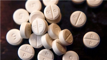 5-mg-Pillen eines Schmerzmittels mit Oxycodon auf einem Tisch. Die großen US-Apothekenketten CVS und Walgreens haben im Rechtsstreit um eine angebliche Mitschuld an der Schmerzmittel-Krise im Land einem teuren Vergleich zugestimmt.