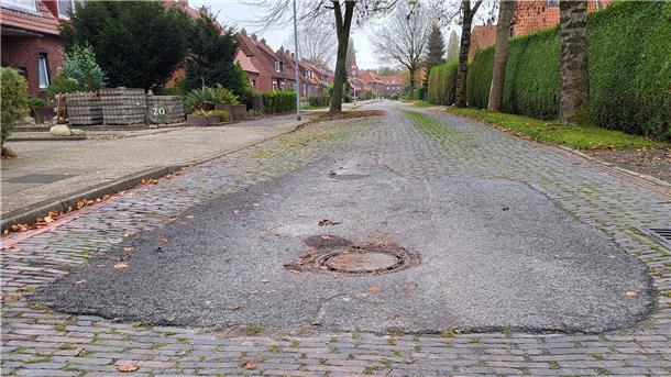 Eine Straße mit Kopfsteinpflaster und einem Kanaldeckel in der Fahrbahnmitte