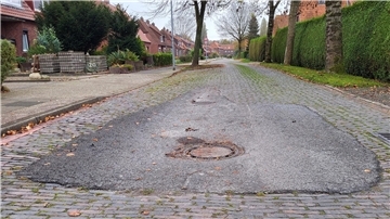 Eine Straße mit Kopfsteinpflaster und einem Kanaldeckel in der Fahrbahnmitte