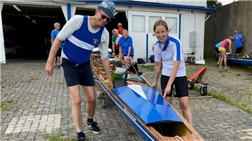 Ein Mann und eine Frau tragen ein Boot zu Wasser