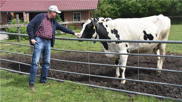 Das Foto zeigt Jan Kaiser mit einer Kuh auf der Weide.