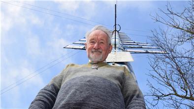 Ein Mann steht vor einem bayerischen Maibaum