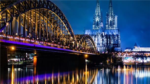 Abendstimmung an der Hohenzollernbrücke in Köln: Langsam nimmt ein Regionalzug Kurs auf den Hauptbahnhof. Im Hintergrund ist der Kölner Dom zu sehen.