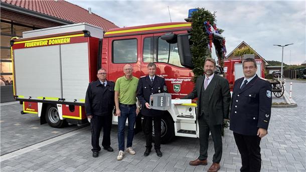 Mehrere Männer stehen vor einem Feuerwehrfahrzeug. 
