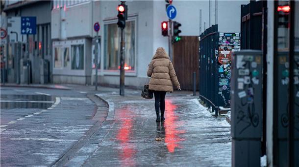 Achtung, glatt: Eine Fußgängerin passiert in Saarbrücken einen Gehweg, der sich nach Blitzeis in eine Rutschbahn verwandelt hat.