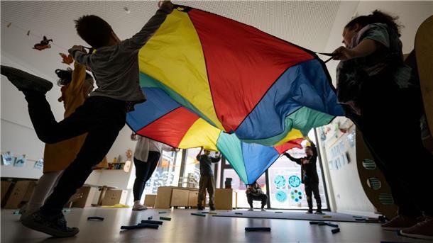 Kinder und Erwachsene spielen mit großem Tuch