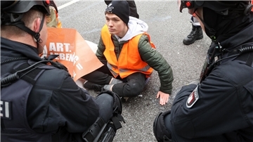 Aktivisten der Umweltgruppe Letzte Generation haben sich auf dem Gorch-Fock-Wall am Stephansplatz in Hamburg festgeklebt und wollen damit auf die Einhaltung der Klimaziele aufmerksam machen. Polizisten sprechen mit den Aktivisten - hier mit Fabian B. aus Zeven.