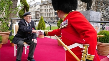 Veteran Alan Kennett schüttelt einem Mitglied der Band of the Irish Guards die Hand.