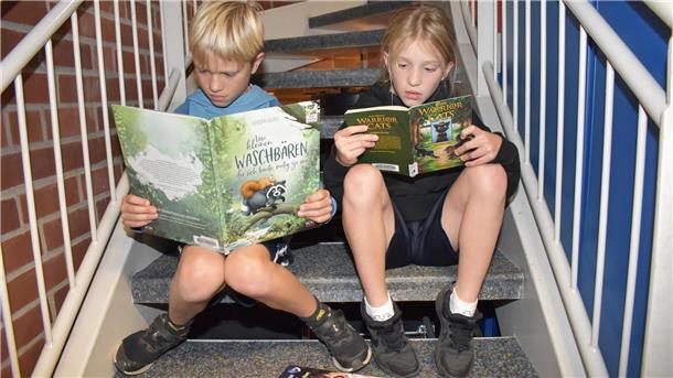 Zwei Kinder sitzen auf einer Treppe und lesen.