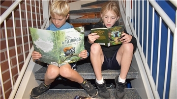 Zwei Kinder sitzen auf einer Treppe und lesen.
