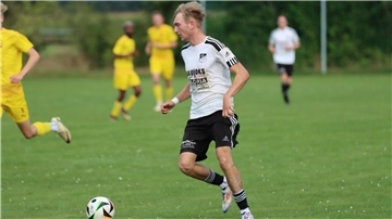 Ein Mann läuft mit einem Ball am Fuß.