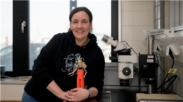 Eine Frau steht mit einer kleinen Puppe in einem Labor. Alexandra Poell mit ihrem Fischereiforschungspüppchen Sandy.