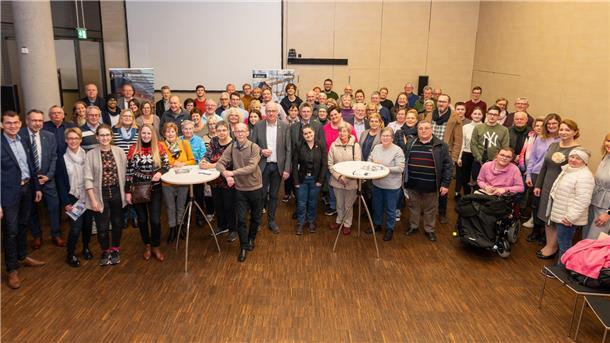 Eine große Gruppe von Menschen steht in einem Saal. 