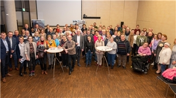 Eine große Gruppe von Menschen steht in einem Saal. 