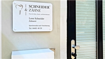 Ein Schild eines Arztes hängt neben einer Tür.
