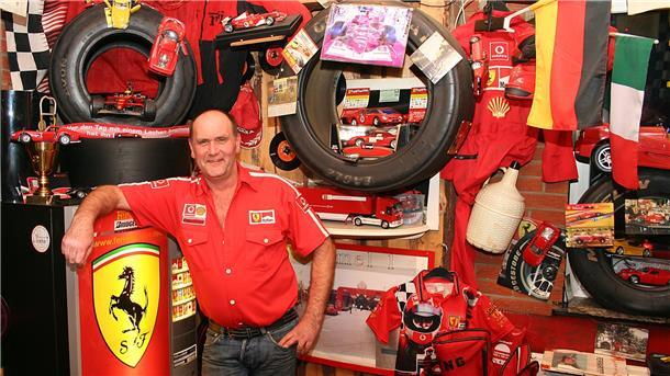 Ein Mann im Ferrari-Dress zeigt Ferrari-Kram.