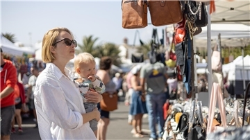 Eine Mutter und ihr Kind stöbern auf einem Flohmarkt.