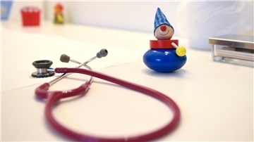 Ein Stethoskop und Kinderspielzeug liegen in einer Kinderarztpraxis auf einem Tisch.