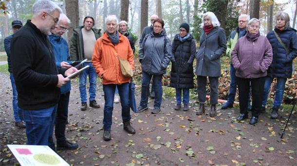 Menschen stehen in einer Reihe im Park und hören zu.