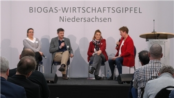 Zuhörer sitzen in Stuhlreihen vor einem Podest.