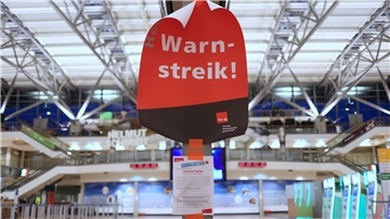 Ein Schild mit der Aufschrift Warnstreik hängt in einem Bahnhof.