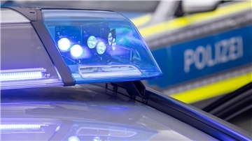 Bild von einem Blaulicht und einem Polizeiwagen im Hintergrund