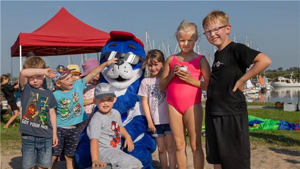 Kinder und ein Seehund-Maskottchen gucken in die Kamera