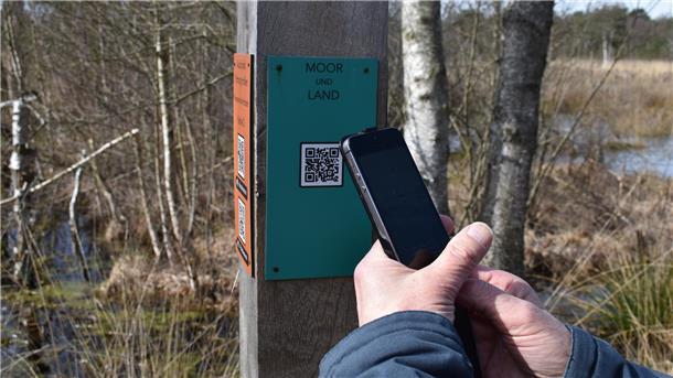 Ein Mann hält sein Telefon vor einen QR Code.