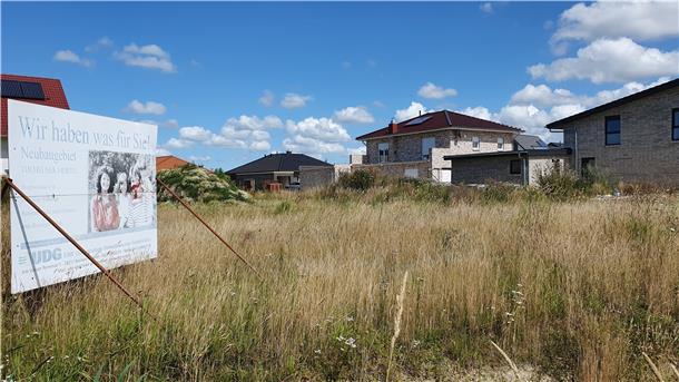 Blick auf eine Wiese in einem Baugebiet mit Schild.