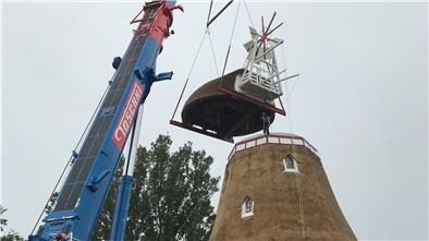 An einer Kette zieht der Dachdecker die sanierte Reetdach-Haube der Beerster Mühle an ihren ursprünglichen Platz.