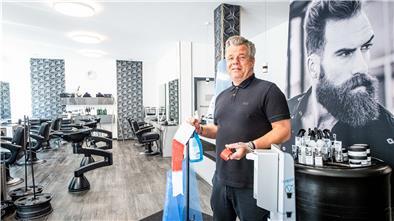 Andre Albers, Inhaber des Friseursalons „Hauptsache“ in der Bremerhavener Georgstraße, bereitet seinen Salon mit Absperrband, Desinfektionsmittelspender und Bodenleitlinien auf den Kundenansturm vor.