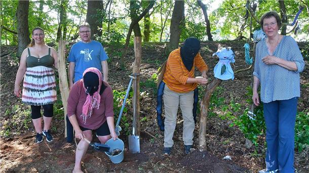 Andrea Priess (vorne) ist als Nashornkäfer verkleidet, Imke Tiedemann (Dritte von links) als Blattschneiderbiene. Gemeinsam mit (von links) Patricia und René Gerhardt sowie Barbara Mohrmann zeigen sie den Besuchern, wie man Totholz für den Insektenschutz nutzen kann.