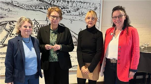 Neujahrsempfang: Ministerin Behrens fordert mehr Einsatz gegen Gewalt an Frauen Vier Frauen stehen nebeneinander in einem Innenraum vor einer großformatigen historischen Zeichnung. Sie tragen unterschiedliche Business- und Freizeitkleidung, darunter Blazer, Blusen und ein rotes Jackett.