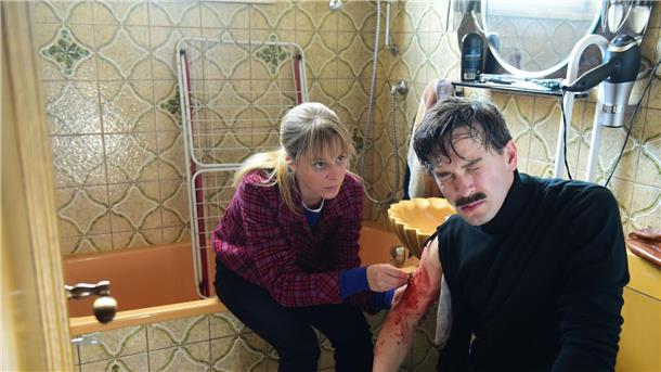 Angelika Flierl (Bernadette Heerwagen) leistet bei ihrem verletzten Entführer (Franz Dinda) erste Hilfe und näht eine Wunde.