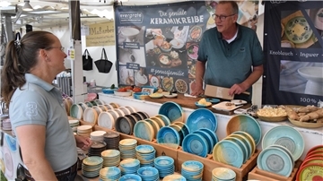 Kundin im Gespräch am Stand mit Keramikreiben.