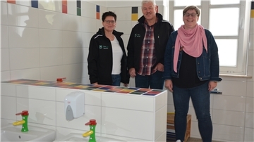 Drei Erwachsene stehen in einem Bad für Kinder. 