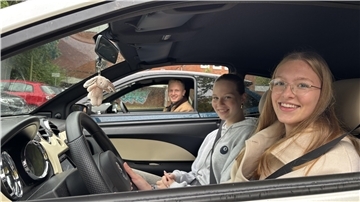 Drei Jugendliche sitzen in Autos und schauen durchs geöffnete Fenster in die Kamera.