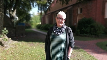 Eine Frau steht vor der Kirche in Loxstedt.