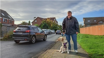 Bild von Helmut Bittner und seiner Labradorhündin in der Bonner Straße, durch die gerade zwei Autos fahren