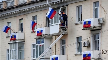 Arbeiter hängen russische Fahnen an einem Wohnhaus in der von Russland unterstützten und von Separatisten kontrollierten Volksrepublik Luhansk auf.